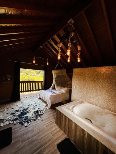 a bedroom with a tub and a bed and a window at LaDomita in Camanducaia