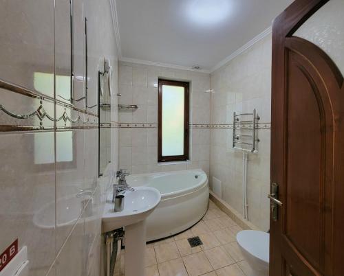 Baño blanco con bañera y lavamanos en Glory en Truskavets