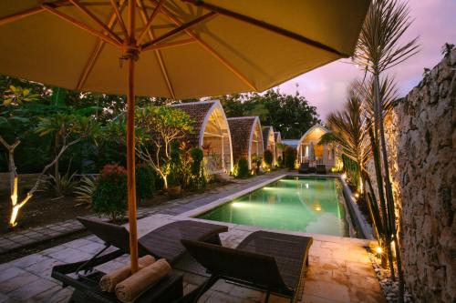 an umbrella and chairs next to a swimming pool at Wage cottage in Nusa Penida