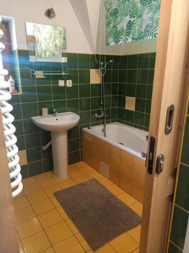 a green tiled bathroom with a sink and a tub at Pokoje u Micka Poronin 5 km od Zakopanego in Poronin