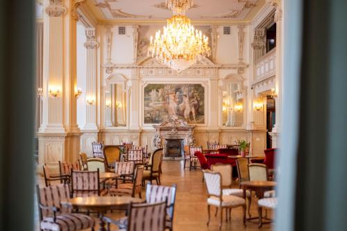 uma sala de jantar com mesas e cadeiras e um lustre em Scuol Palace Bed & Breakfast em Scuol