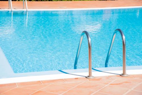 a swimming pool with blue water and two metal rails at Hotel Santa Gilla in Capoterra