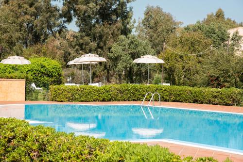 a swimming pool with two umbrellas and a pool at Hotel Santa Gilla in Capoterra