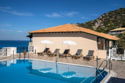a pool with chairs and umbrellas next to the ocean at Sunset Premium Studio 7 in Agios Nikitas