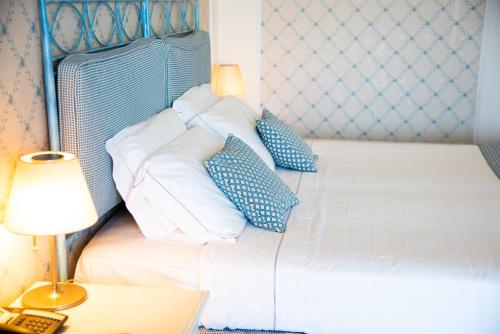 a bedroom with a bed with blue and white pillows at Hotel Santa Gilla in Capoterra