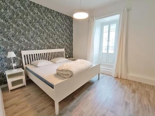 a white bed in a bedroom with a wall at Le Télécab', T5, wifi, cave, ascenseur, 8 personnes in Luchon