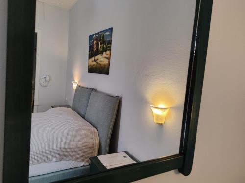 a mirror reflecting a bedroom with a bed and a lamp at Sidra Hotel in Hydra