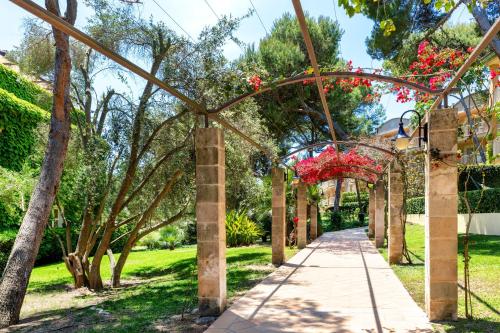 una pasarela en un jardín con flores rojas en VIVA Cala Mesquida Suites & Spa Adults Only 16, en Cala Mesquida