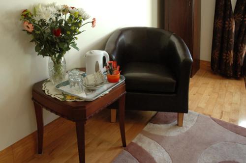 a black chair and a table with a vase of flowers at Caldra B&B in Buncrana