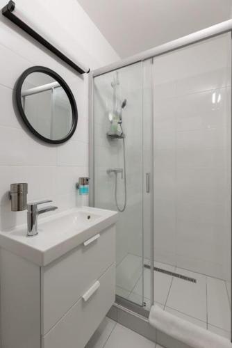 a white bathroom with a sink and a shower at Lorent2 Apartman in Balatonföldvár