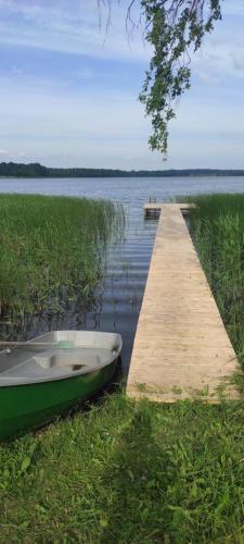 a boat sitting on the grass next to a dock at Ezernams SPA in Kaukuri