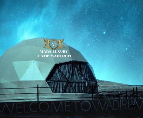 un bâtiment en forme de dôme avec un panneau la nuit dans l'établissement MARS LUXURY CAMP WADi RUM, à Wadi Rum