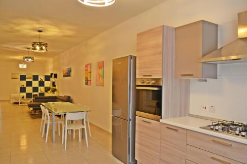 a kitchen with a table and a refrigerator at Ivy Rose - Marsaxlokk in Marsaxlokk