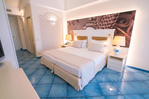 a bedroom with a large white bed and blue tile floors at Hotel Santa Gilla in Capoterra