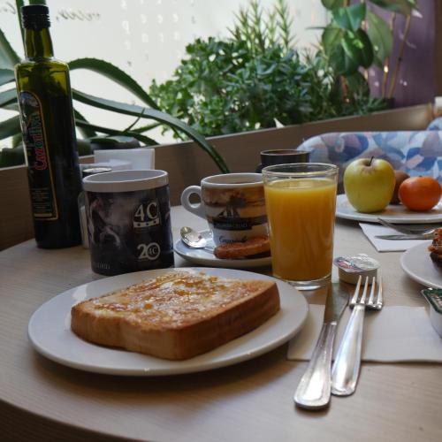 a table with a plate of bread and cups of orange juice at Hostal 4C Cuatro Caminos in Madrid