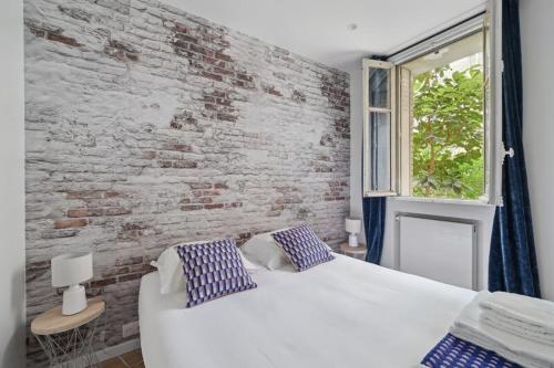 une chambre avec un lit blanc et un mur de briques dans l'établissement 540 Suite Meridien - Superbe Appartement à Paris, à Paris