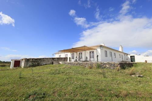 a white house on top of a grassy hill at Country House and Estate - Herdade da Azinheira in Pavia