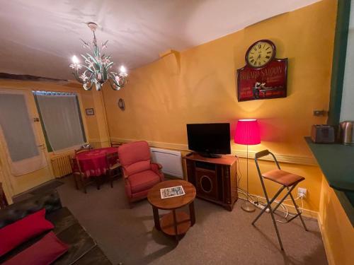 un salon avec un canapé et une horloge au mur dans l'établissement Chez Odette, à Pradelles