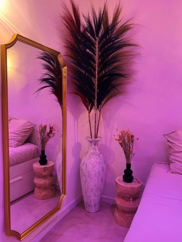 une pièce violette avec un miroir et un vase avec des fleurs dans l'établissement Les nuits d’Ina, à Toulon
