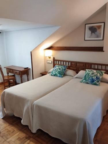 two beds in a hotel room with a table at Hotel Los Hidalgos in Santillana del Mar