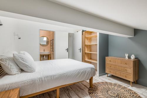 - une chambre avec un lit blanc et une armoire en bois dans l'établissement COZY HAVEN Appart. industriel neuf proximité hôpital Bellevue, à Saint-Étienne