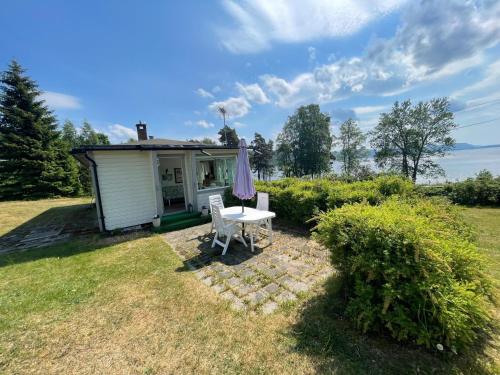 een klein huisje met een tafel en een paraplu bij Furuly by Norgesbooking - cabin 20 meters from the beach in Hyggen