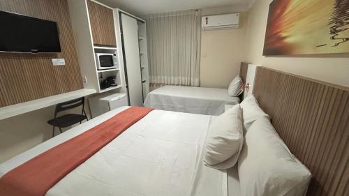a hotel room with two beds and a tv at Mar de Ponta Negra in Natal