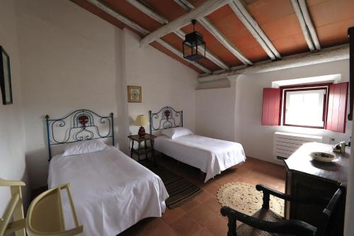 a bedroom with two beds and a table and a window at Country House and Estate - Herdade da Azinheira in Pavia