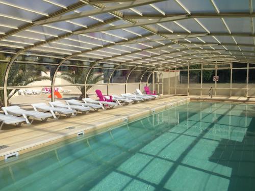 - une piscine avec des chaises blanches dans l'établissement NUIT INSOLITE - Côte de granit rose - Camping Armor Loisirs, à Trébeurden