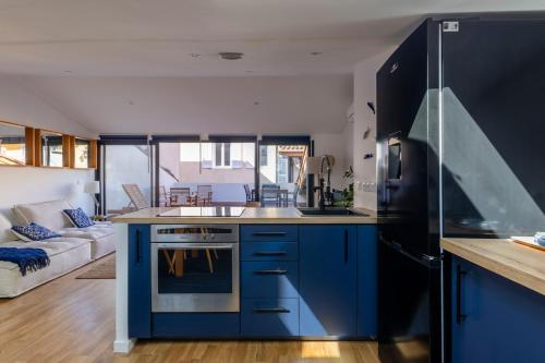 a kitchen with blue cabinets and a black refrigerator at La maison des canailles in Cassis