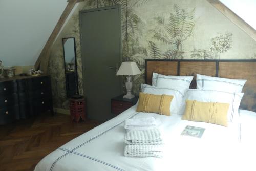 um quarto com uma cama grande e almofadas brancas em Le Clos Luly em Neulliac