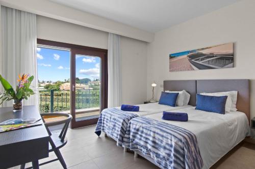 a hotel room with a bed and a balcony at Vale de Milho Village in Carvoeiro