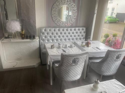 uma sala de jantar com uma mesa, cadeiras e um espelho em The Cosy Nook em Blackpool