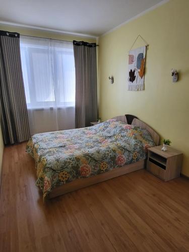 1 dormitorio con 1 cama con colcha de flores en Giedres apartaments-Alkava, en Kaunas