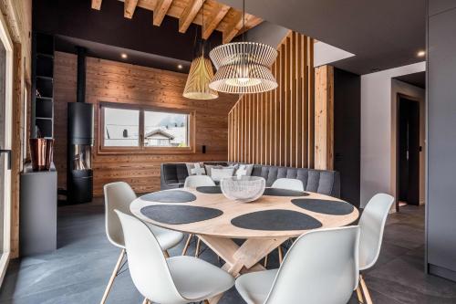 a dining room with a wooden table and white chairs at Apartment Neuenhaus 4.5 – GRIWA RENT AG in Grindelwald