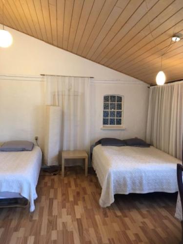 a bedroom with two beds and a wooden floor at Motel Villa Søndervang 3 personers værelse in Harndrup