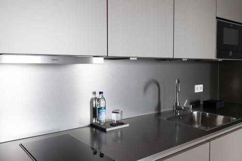a kitchen counter with two bottles and a sink at Toploft The Aparthotel in Crailsheim