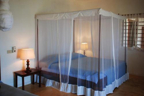 a bedroom with a bed with a canopy and two lamps at Villa Palissandre in Nosy Be