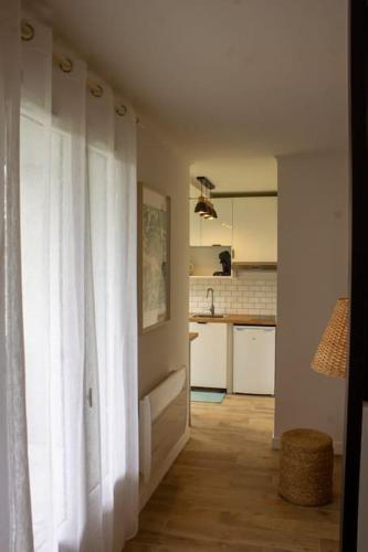 une pièce avec une cuisine avec un rideau blanc dans l'établissement Appartement - terrasse - Cugnaux centre, à Cugnaux