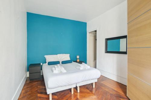 une chambre avec un lit blanc avec un mur bleu dans l'établissement 554 Suite Laitière - Superbe appartement, à Vincennes