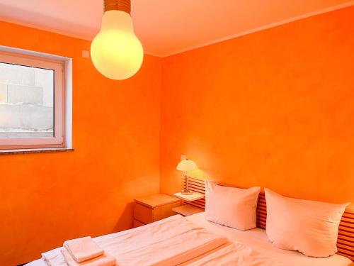una camera da letto con pareti arancioni e un letto con cuscini bianchi di Ferienhaus Salzhaffblick a Rerik