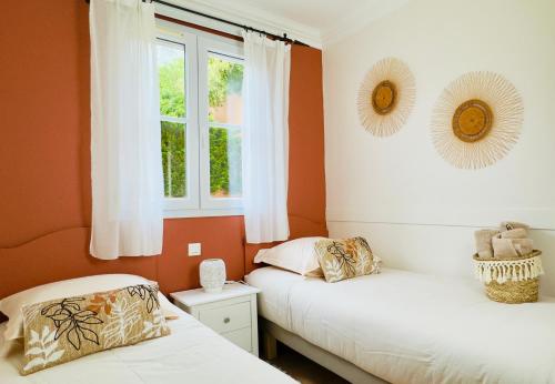 Ce lit se trouve dans un dortoir doté de murs orange et d'une fenêtre. dans l'établissement Les Restanques vue mer Bastide rez jardin 3021, à Grimaud