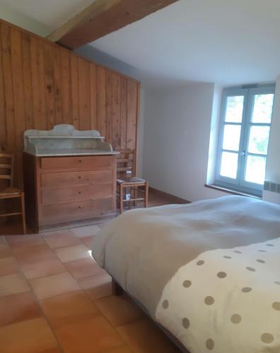 une chambre avec un lit, une commode et une fenêtre dans l'établissement Le Pigeonnier au dessus du lac, à Caraman