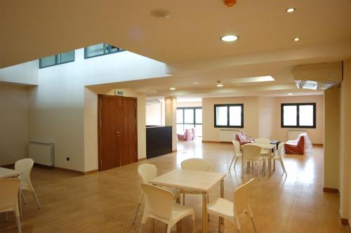 una habitación con mesas y sillas y una habitación con ventanas en Apartamentos Turísticos Vicotel, en Teruel