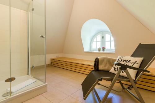 a bathroom with a glass shower and a chair at An den Boddenwiesen 02 in Wieck