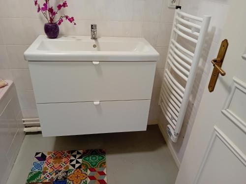 La salle de bains est pourvue d'un lavabo blanc et d'un radiateur blanc. dans l'établissement CONFORTABLE T3 sur BALCON à 5 MN du Centre Ville, à Bayonne