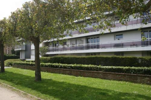 ein Apartmenthaus mit einem Baum im Gras in der Unterkunft La Belle Vie Ouistreham Riva Bella Résidence Hastings in Ouistreham