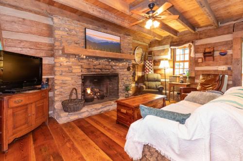 a log cabin bedroom with a fireplace and a tv at Old Chestnut Cabin at Lake Junaluska in Waynesville