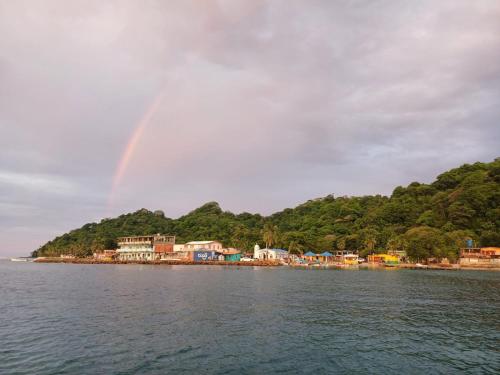 a rainbow in the sky over a town on the water at Cabaña La Punta in Isla Grande