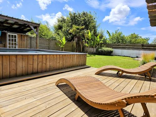 a wooden deck with two chairs and a swimming pool at Spacieuse maison avec piscine, 9km de l'océan. in Tosse